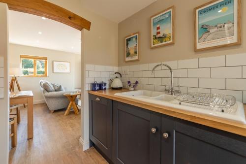 a kitchen with a large sink and a living room at Tudor Rose in Aylsham