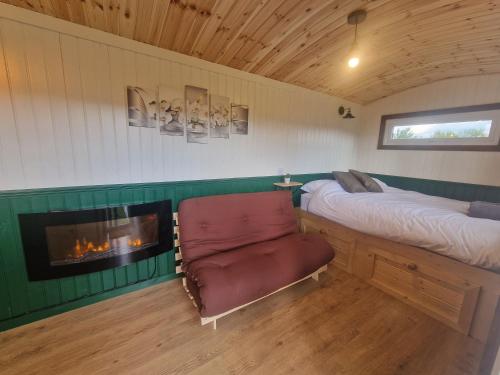 a bedroom with a bed and a chair and a fireplace at Cwtch Glamping Shepherds Huts in Abergavenny
