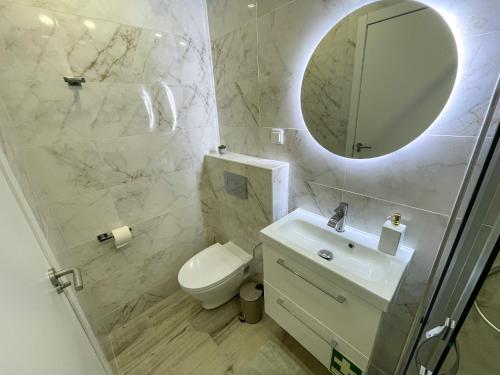 uma casa de banho com um WC, um lavatório e um espelho. em Our Charming House em Portimão