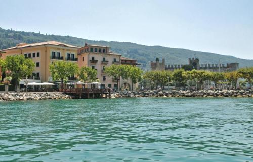 a body of water with a group of buildings at Hotel Del Porto in Torri del Benaco