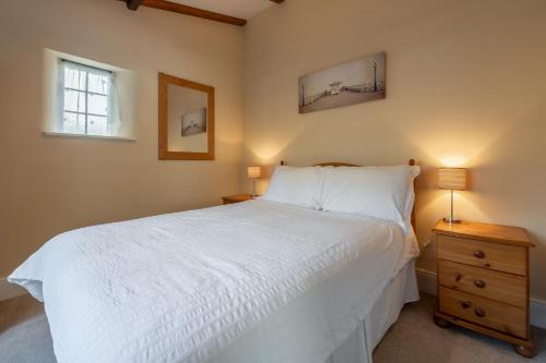 a bedroom with a white bed and a wooden nightstand at Crabpot Cottage in West Runton