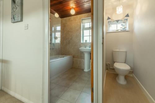 a bathroom with a toilet and a tub and a sink at Crabpot Cottage in West Runton