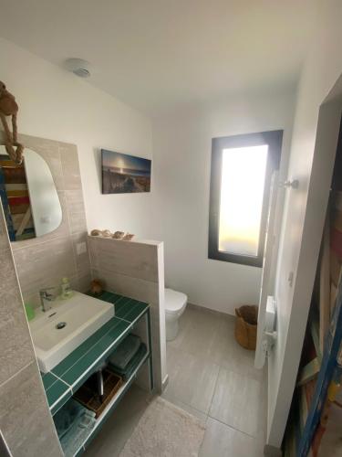 a bathroom with a sink and a toilet and a mirror at La chambre de Séraphine in Biscarrosse