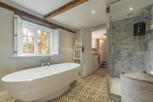 a bathroom with a white tub and a shower at Barn Cottage 6 in Salthouse