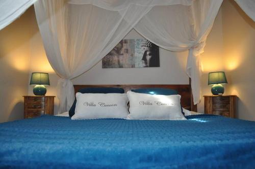 um quarto com uma cama azul e 2 almofadas em La Villa Cocoon prestige et vue mer em Sainte-Luce