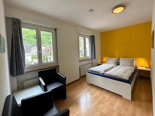 um quarto com uma cama, uma cadeira e 2 janelas em alscher's holiday home em Interlaken