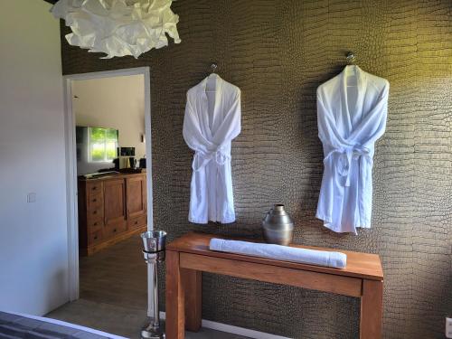 three white robes hanging on a wall next to a table at LUXE Bloemenzicht 4 personen, BnB, 10 minuten van zee in Breezand