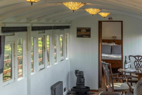 a room with a table and a bed and lights at The Railway Carriage in Melton Constable