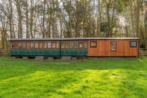 a train car sitting in a field of grass at The Railway Carriage in Melton Constable