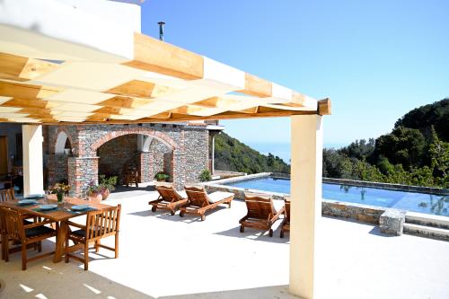 un patio con mesa, sillas y piscina en Villa Krio Pigadi en Kechria