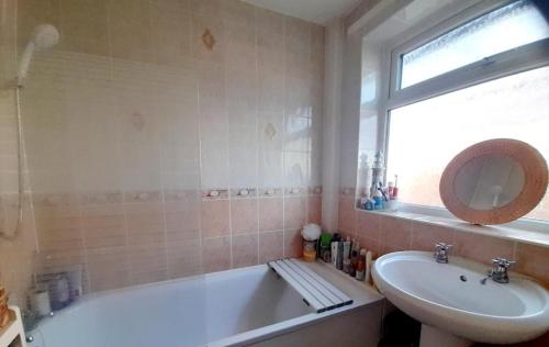 a bathroom with a tub and a sink and a mirror at Spacious Bungalow in Pinxton