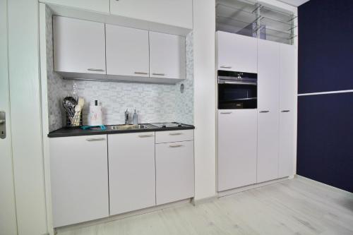 a white kitchen with white cabinets and a sink at Ferien am Luganer See mit Seesicht in Bissone