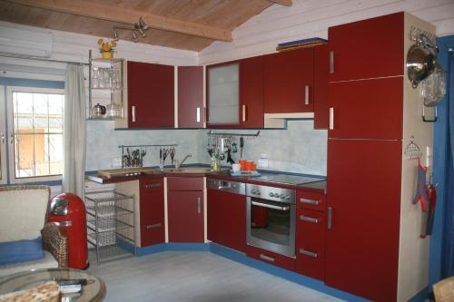 a red kitchen with red cabinets and a sink at Rotes Haus Usedom in Kamminke