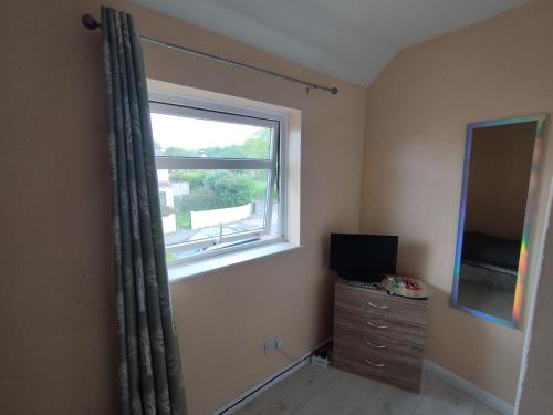 a bedroom with a window and a dresser with a television at We love Henbury in Bristol