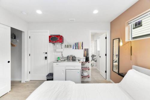 a white bedroom with a white bed and a kitchen at Chase's sweet suite - Micro Studio - 91Walkscore in Seattle