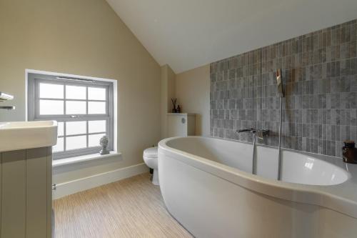 a bathroom with a large tub and a toilet at Foxhill House in South Creake