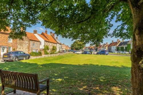 a park bench under a tree in a residential neighborhood at Foxhill House in South Creake