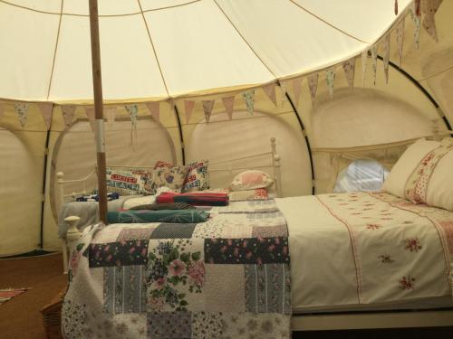 a bedroom with a bed with a quilt on it at Horsemans Stargazing Tent in Kingsbridge