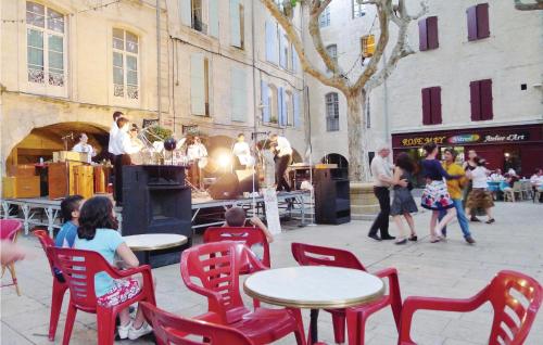 un groupe de personnes assises sur des chaises et des tables rouges dans une rue dans l'établissement Cozy Apartment In Beaucaire With Wifi, à Beaucaire
