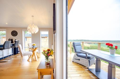 a kitchen and dining room with a balcony with a table and chairs at Avocet Lodge in Ingoldisthorpe
