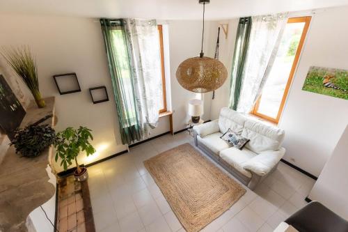ein Wohnzimmer mit einem weißen Sofa und Fenstern in der Unterkunft Maison La Cigogne Noire in La Loge-aux-Chèvres