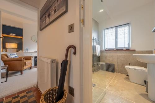 a bathroom with a mop leaning against a wall at Tide Cottage WR in West Runton