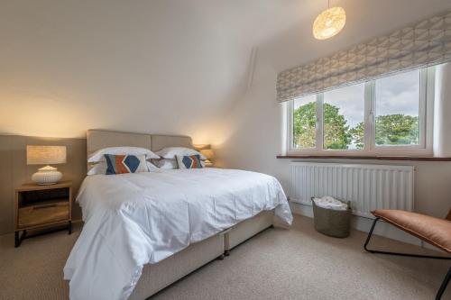 um quarto com uma cama com lençóis brancos e uma janela em Tide Cottage WR em West Runton