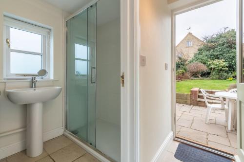 a bathroom with a glass shower and a sink at Arisaig in Wells next the Sea