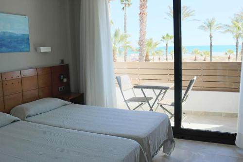 a bedroom with two beds and a balcony with a table at Hotel Costa Azahar in Grao de Castellón
