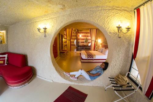 a woman is sitting on the floor in a room with a round mirror at Hezen Cave Hotel in Ortahisar