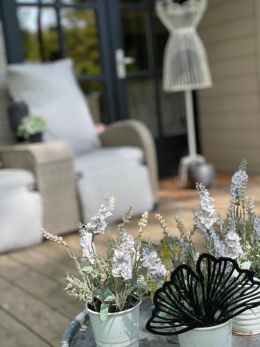 two white vases with flowers on a table at Chalet Sint-Hubertus Deluxe in Zutendaal