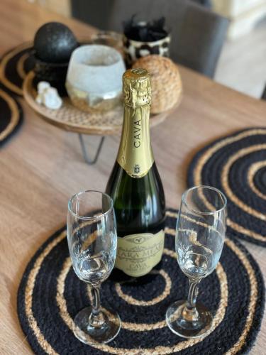a bottle of wine and two wine glasses on a table at Chalet Sint-Hubertus Deluxe in Zutendaal