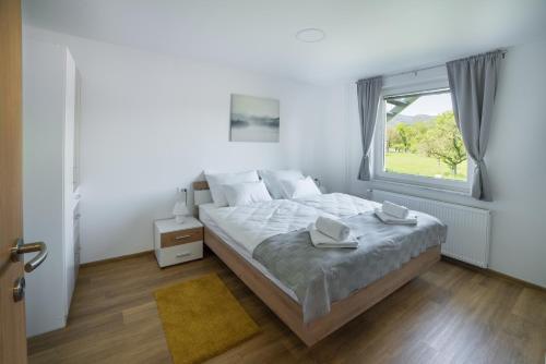 a white bedroom with a large bed and a window at Apartma Lida 1 in Bled