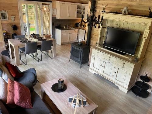 a living room with a large television and a kitchen at Chalet Sint-Hubertus Deluxe in Zutendaal