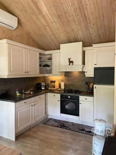 a kitchen with white cabinets and a black stove at Chalet Sint-Hubertus Deluxe in Zutendaal