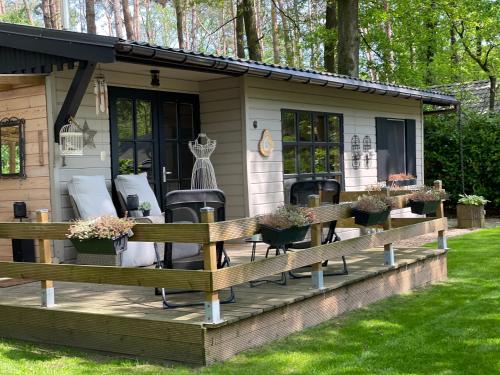 a tiny house with a porch and chairs at Chalet Sint-Hubertus Deluxe in Zutendaal