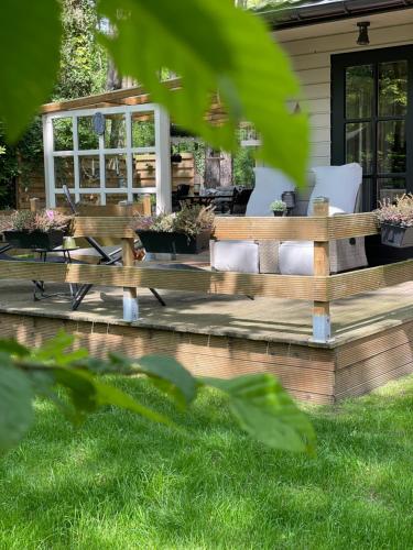 a wooden deck with white chairs in front of a house at Chalet Sint-Hubertus Deluxe in Zutendaal