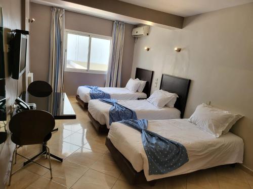 a hotel room with three beds and a television at Résidence Hotelière Fleurie in Agadir