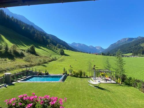 a backyard with a swimming pool in a green field at Hotel LÄRCHENHOF in Kleinarl