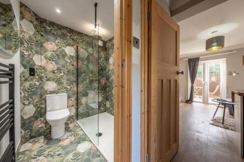a bathroom with a toilet and a glass shower at Coach House Cottage in Weybourne