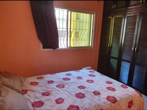 1 Schlafzimmer mit einem Bett mit einer Blumendecke und einem Fenster in der Unterkunft Agadir in Agadir