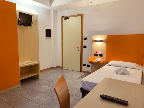 a room with two beds and a table and a television at Hotel Grecale - Venturina Terme in Venturina Terme