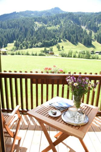 a wooden table with a vase of flowers on a balcony at Hotel LÄRCHENHOF in Kleinarl