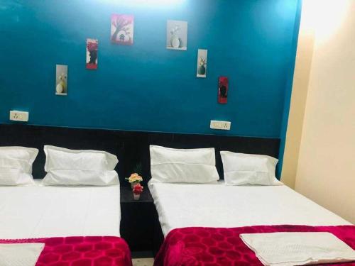 2 Betten in einem Zimmer mit blauer Wand in der Unterkunft OYO The Bliss Guest House & Restaurant in Gwalior