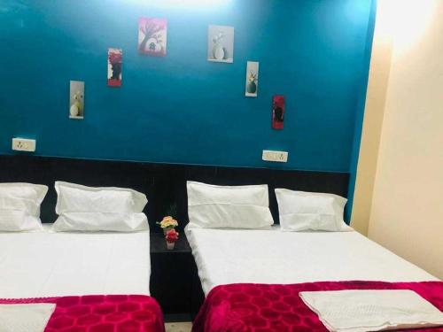two beds in a room with a blue wall at OYO The Bliss Guest House & Restaurant in Gwalior