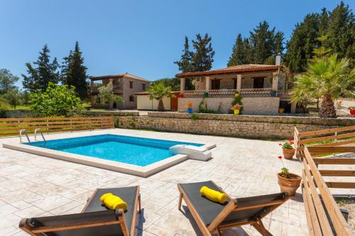 a backyard with a pool and two chairs and a house at Liuba Villas in Vasilikos