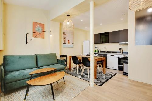 uma sala de estar com um sofá verde e uma cozinha em New and bright apartment 4 people em Paris
