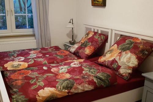 uma cama com um edredão vermelho e duas almofadas em Ferienwohnung am Wald **** 