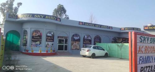 OYO Hotel Sky Bird في Pehowa: سيارة بيضاء صغيرة متوقفة أمام متجر