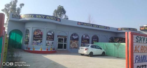 un pequeño coche blanco estacionado frente a una tienda en OYO Hotel Sky Bird en Pehowa